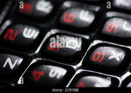 Physische Tastatur eines alten Telefons. Schwarze Tasten, rote Zahlen und weiße Buchstaben. Stockfoto