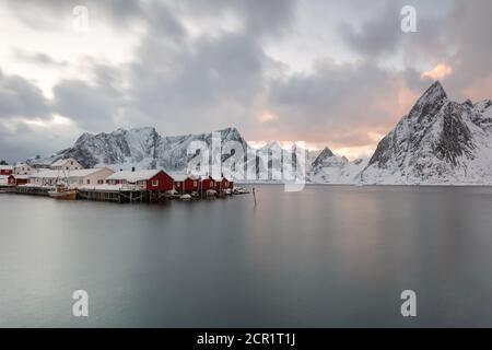 Landschaft der Lofoten-Inseln in Norwegen mit traditionellem Holz Rote Fischerhütten vor dem Meer und dies Schöne Moutain im Hintergrund Stockfoto
