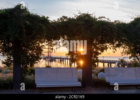 Deutschland, Mecklenburg-Vorpommern, Rügen, Ostseebad Binz, Seebrücke und Bänke im Kurpark kurz vor Sonnenaufgang Stockfoto