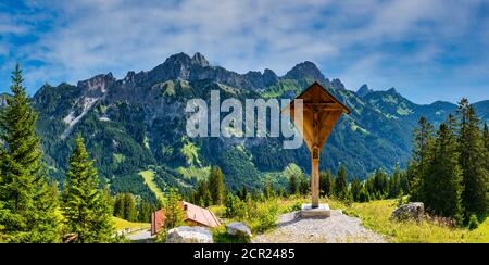 Holzkreuz an der Krinnenalpe, 1530m, dahinter Friedberger Klettersteig, Rote Flüh, 2108m, Gimpel, 2173m und Köllenspitze, 2238m, Tannheimer Berge, Stockfoto