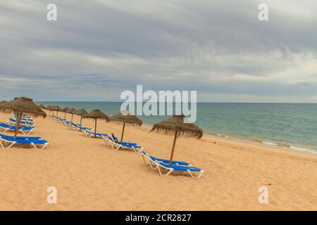 Leerer einsamer Strand mit niemand in den Liegestühlen in Faro, Algarve während der Covid-19 Pandemiebeschränkungen. Stockfoto