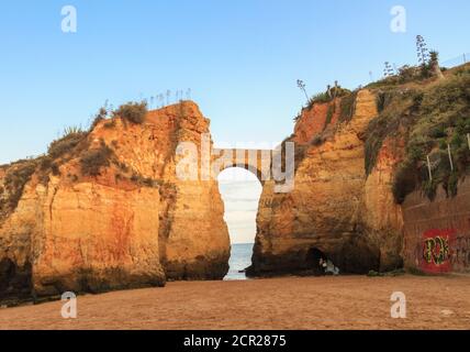 Strand Praia dos Estudantes bei Sonnenuntergang mit Bogenbrücke in Lagos, Algarve, Portugal Stockfoto