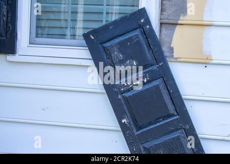 Ein schwarzer Fensterverschluss, der kaum an der weißen Wand hing Stockfoto