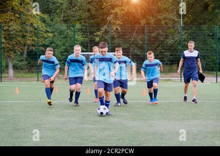 Kinder laufen und treten Fußball auf Fußball-Trainingseinheit Stockfoto