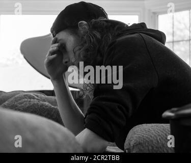 Eine Schwarz-Weiß-Aufnahme von einem gestressten und Verärgert junger Mann in einem Hut Stockfoto