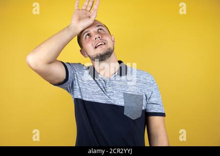 Russischer Mann, der über dem verlösten gelben Hintergrund steht, der die Stirn für Krankheit und Fieber, Grippe und Erkältung berührt, viruskrank Stockfoto