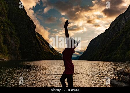 Eine Frau fühlt sich am Fjord glücklich Stockfoto