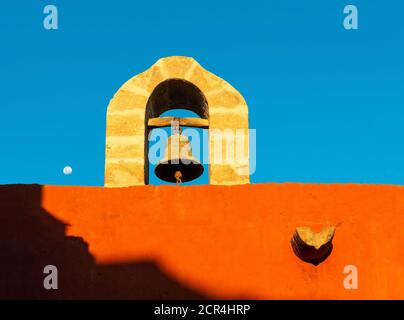 Alte Glocke mit Bogen und Mond bei Sonnenuntergang im Kloster Santa Catalina, Arequipa, Peru. Stockfoto