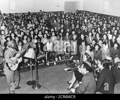 Huddie William Ledbetter (1888-1949), ein Folk- und Bluesmusiker, besser bekannt unter seinem Künstlernamen 'Leadbelly', tritt vor einem Publikum von Jugendlichen im High School-Alter auf und begleitet sich selbst auf seiner 12-saitigen Gitarre, San Francisco, CA, 1949. (Foto von RBM Vintage Images) Stockfoto