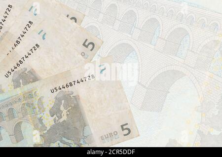 5 Euro Scheine liegen im Stapel auf dem Hintergrund der großen halbtransparenten Banknote. Abstrakter Geschäftshintergrund mit Kopierbereich Stockfoto