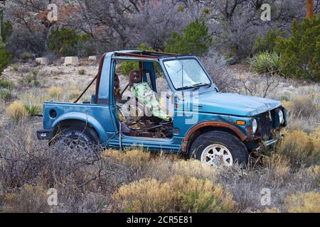 Heruntergekommenes blaues älteres Auto auf einem Feld in der Wüste Querformat Stockfoto