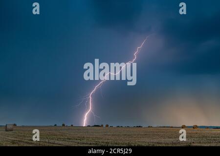 Gewitter mit Blitzschlag über einem Stoppelfeld in Thüringen, Deutschland. Stockfoto