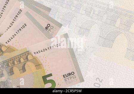 5 Euro Scheine liegen im Stapel auf dem Hintergrund der großen halbtransparenten Banknote. Abstrakter Geschäftshintergrund mit Kopierbereich Stockfoto