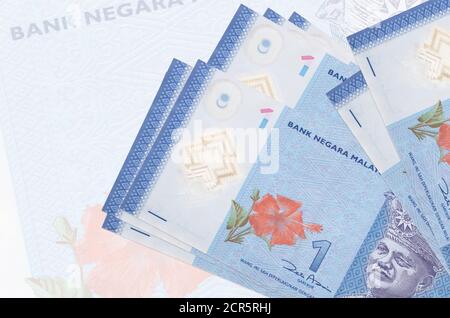 1 malaysische Ringgit-Scheine liegt im Stapel auf dem Hintergrund einer großen halbtransparenten Banknote. Abstrakte Darstellung der nationalen Währung. Geschäftskonzept Stockfoto