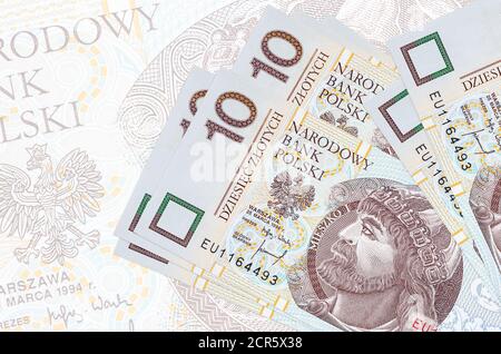 10 polnische Zloty-Scheine liegen im Stapel auf dem Hintergrund einer großen halbtransparenten Banknote. Abstrakte Darstellung der nationalen Währung. Geschäftskonzept Stockfoto