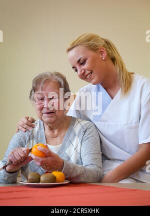 Generationen im Dialog. In der Tagesklinik einer geriatrischen Einheit wird ein Patient während der täglichen Übungen von einer jungen Frau ehrenamtlich betreut Stockfoto