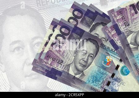 100 philippinische Piso-Scheine liegen im Stapel auf dem Hintergrund einer großen halbtransparenten Banknote. Abstrakte Darstellung der nationalen Währung. Geschäftskonzept Stockfoto