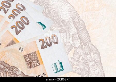 200 tschechische korun-Scheine liegen im Stapel auf dem Hintergrund der großen halbtransparenten Banknote. Abstrakter Geschäftshintergrund mit Kopierbereich Stockfoto
