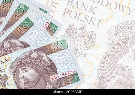 10 polnische Zloty-Scheine liegen im Stapel auf dem Hintergrund einer großen halbtransparenten Banknote. Abstrakter Geschäftshintergrund mit Kopierbereich Stockfoto