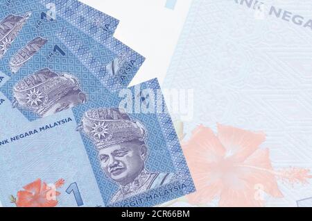 1 malaysische Ringgit-Scheine liegt im Stapel auf dem Hintergrund einer großen halbtransparenten Banknote. Abstrakter Geschäftshintergrund mit Kopierbereich Stockfoto