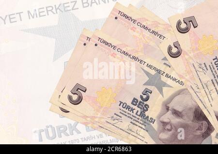 5 türkische Lira-Scheine liegen auf dem Hintergrund einer großen halbtransparenten Banknote. Abstrakte Darstellung der nationalen Währung. Geschäftskonzept Stockfoto