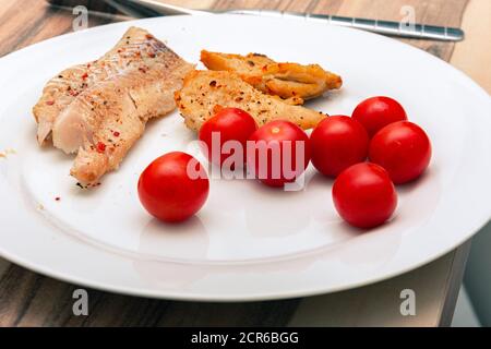 Leckere Kirschtomaten mit würzigen Fischen auf einem weißen Teller Stockfoto