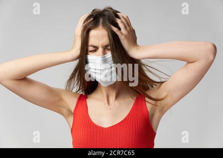 Eine Frau hält ein rotes T-Shirt am Kopf Eine medizinische Maske mit Stockfoto