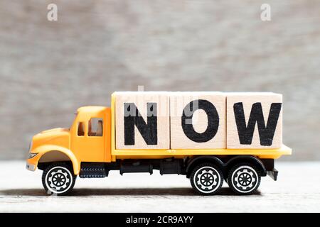 LKW halten Buchstabenblock in Wort jetzt auf Holz Hintergrund Stockfoto