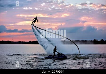 Rocket man fliegt auf einem Jet Fly Board bei Sonnenuntergang in Lake Arlington, Texas. Stockfoto