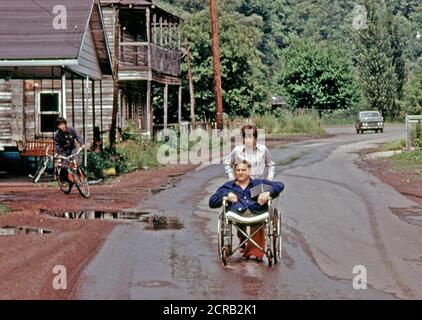 Jack Smith, 42, Behinderte Miner in Rhodell, WV, wird auf der Straße von seiner Tochter, 16, in die Bar betreibt er mit Rädern. Er arbeitete in den Minen ein Jahr, als seine Beine zerquetscht wurden. 1974 Stockfoto