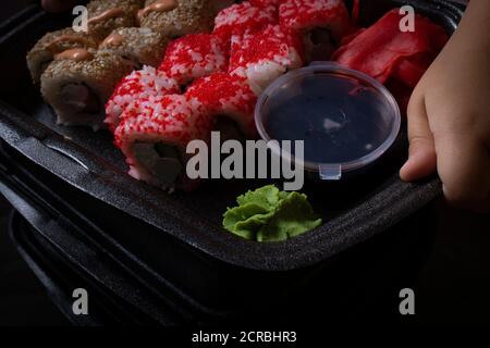 Kinder Hände halten Black Box mit Sushi-Rollen, Nahaufnahme Stockfoto