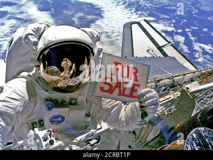 Astronaut Dale A. Gardner, der gerade den größten Teil seines zweiten Extra Vehicular Activity (EVA) Zeitraum in drei Tagen, hält ein Schild "Zum Verkauf" bezieht sich auf die beiden Satelliten, Stockfoto