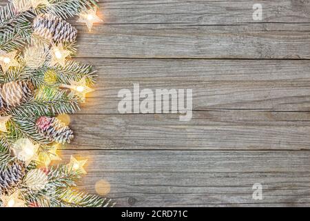 Frostiger weihnachtsbaum Zweig auf Holzoberfläche mit glühenden Feiertagsbeleuchtung. Festlicher Hintergrund mit Kopierraum Stockfoto