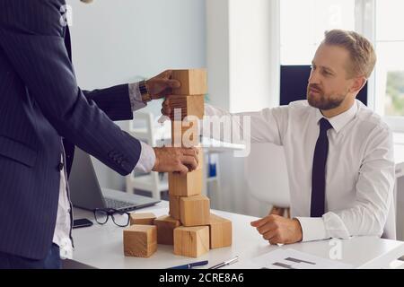 Partner bauen Turm aus Holzblöcken auf Bürotisch gemeinsam entwickeln Strategie für Unternehmen. Stockfoto
