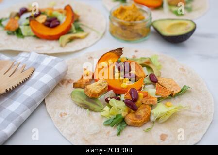 Offene vegane Tortilla Wraps mit Süßkartoffeln, Bohnen, Avocado und Kürbis Stockfoto