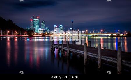 Düsteres Nachtbild der Stadt Perth aus der Old Swan Brewery. Die Anlegestelle weist auf die Narrows-Brücke und die Skyline der Stadt. Stockfoto