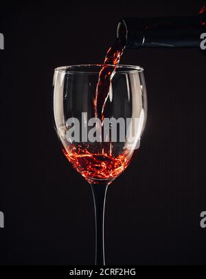 Rotwein gießen Glas auf braunem Hintergrund Stockfoto