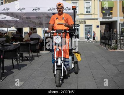 Belgrad, Serbien, 17. Sep 2020: Straßenszene mit einem Müllmann auf dem offiziellen Elektro-Dreirad Stockfoto