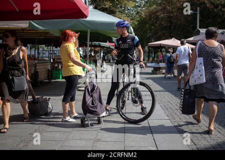 Belgrad, Serbien, 17. Sep 2020: Straßenszene mit einer Frau, die sich mit dem Radfahrer auf dem Bauernmarkt unterhielt Stockfoto