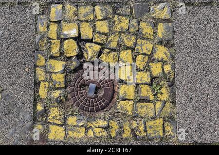 Draufsicht auf eine runde Kanalluke aus Metall auf einem Steinpflaster Stockfoto