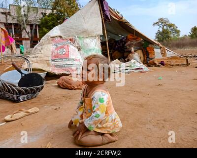 DISTRIKT KATNI, INDIEN - 29. JANUAR 2020: Ein indisches Dorf arme weibliche Kind sitzt auf dem Boden Feld in Himmel Hintergrund. Stockfoto