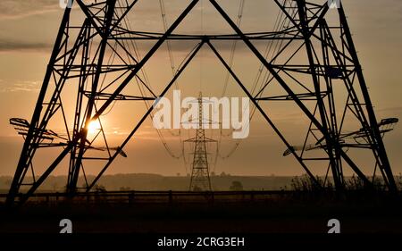 Nationale Netz Stromversorgung Pylon Turm unteren Abschnitt Silhouette Rahmen entfernten elektrischen Pylon Türme Unterstützung Stromleitungen bei Sonnenaufgang. Stockfoto