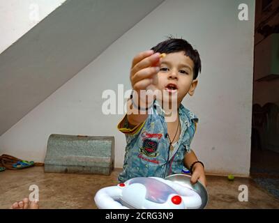 DISTRIKT KATNI, INDIEN - 21. MAI 2020: Ein süßer indischer Junge, der zu Hause Essen für die Kamera anbietet. Stockfoto