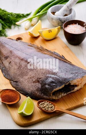 Roher frischer Heilbutt ohne Kopf auf Holzschneidebrett Stockfoto