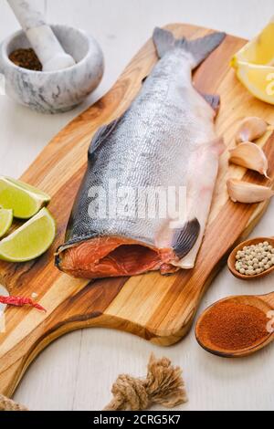 Roher frischer kopfloser rosa Lachs auf Holzschneidebrett Stockfoto