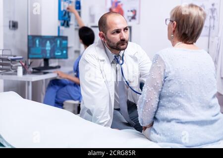 Medizinische Beratung für Rentner, während sie auf Krankenhausbett sitzt. Prüfung für Rentner. Gesundheitswesen Medizin System, Arzt Behandlung Stockfoto