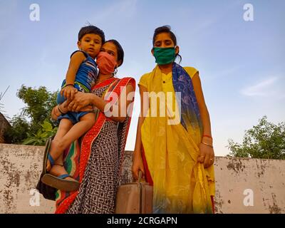 DISTRIKT KATNI, INDIEN - 21. MAI 2020: Indische Mutter trug sein kleines niedliches Baby auf dem Schoß, während sie Gesichtsmast für Corona-Virus-Schutz trug. Stockfoto