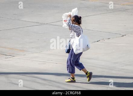 SAMUT PRAKAN, THAILAND, 23 2020. JULI, eine Frau geht auf der Straße und bedeckt ihr Gesicht mit der Tasche gegen das Sonnenlicht. Stockfoto