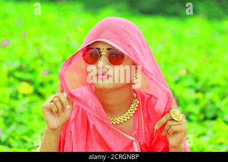 Ein Nahaufnahme Porträt Bild von indischen schönen jungen Frau Gesicht Mit tragen rosa farbigen traditionellen Rajasthani rajputi Kleid und glänzend Elegante Brille Stockfoto