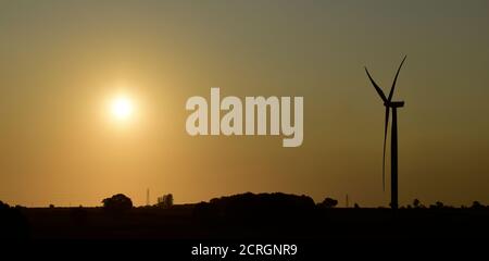 Silhouette der Windturbine auf dem Burton Wold Windpark bei Sonnenaufgang. Nachhaltige Null-Kohlenstoff-Strom über Windgenerator, grüne Energie. Stockfoto